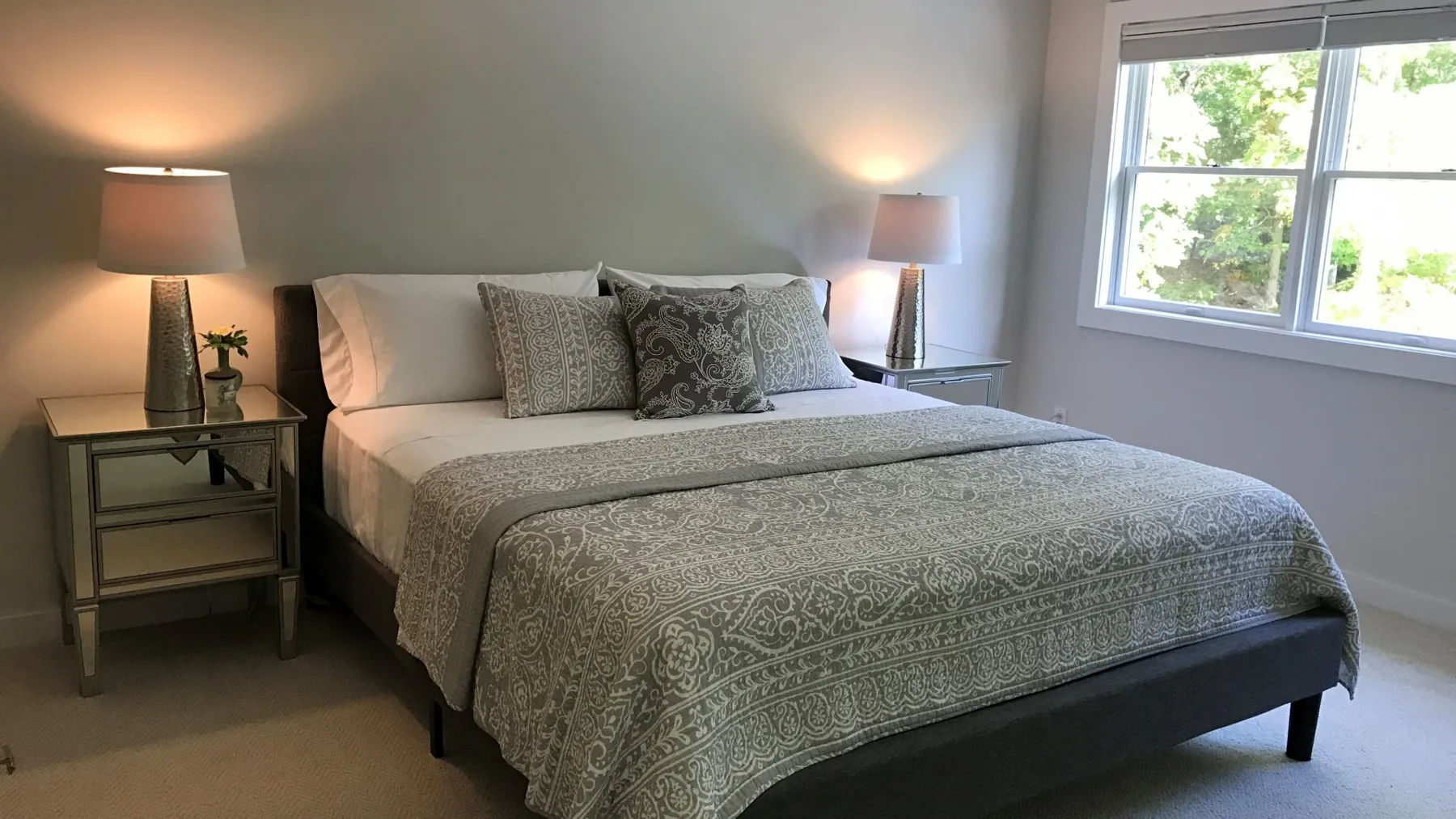 A bedroom with a neatly made bed and bedside lamps.