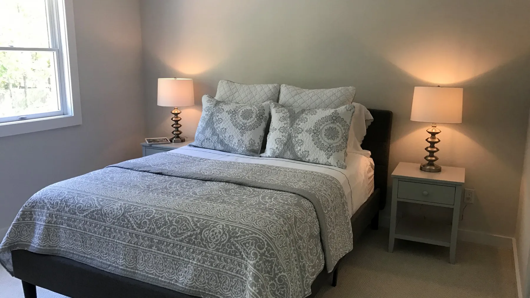 A bedroom with a neatly made bed and matching bedside lamps.