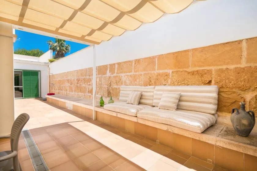 A sunny patio with cushioned seating beneath a fabric canopy.