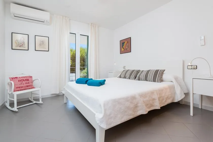 A bright bedroom with a large bed and glass doors opening onto greenery.