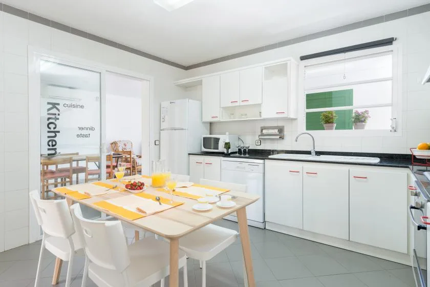 A bright kitchen and dining area with white cabinets and a set table.