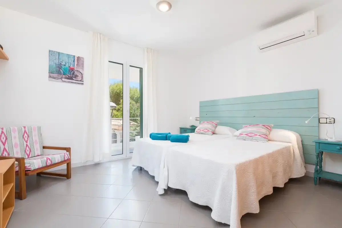 A bright bedroom with a double bed and glass doors opening to a balcony.
