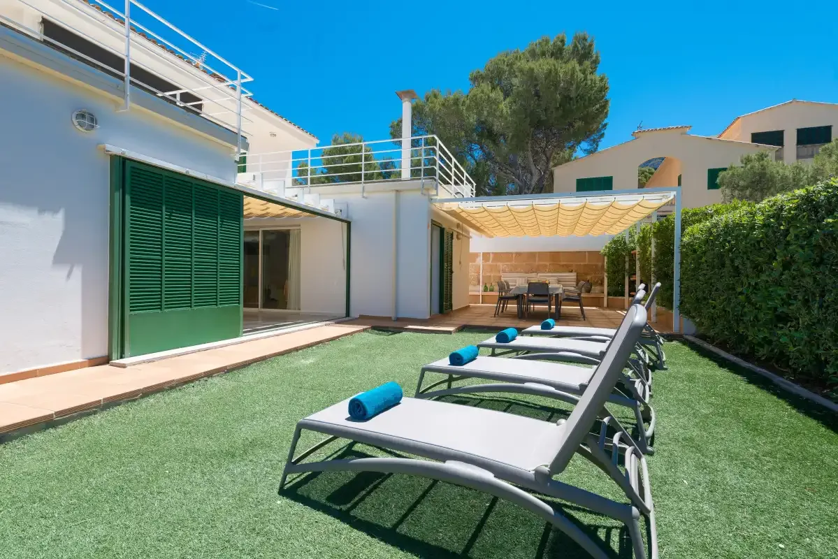 An outdoor patio with lounge seating, artificial turf, and a shaded dining area.