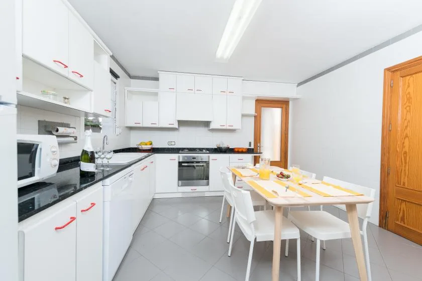A bright kitchen with white cabinets and a dining table set for a meal.