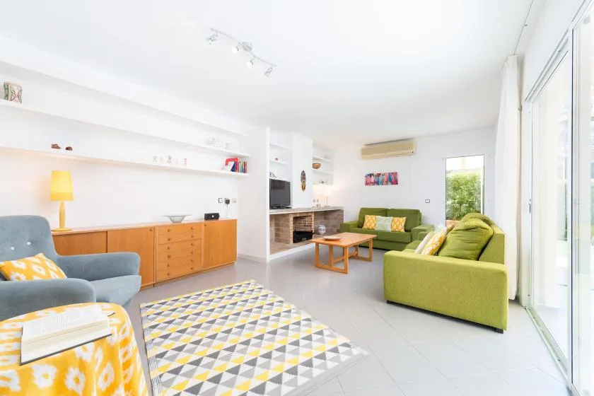 A bright living room with green seating, a coffee table, and large windows.