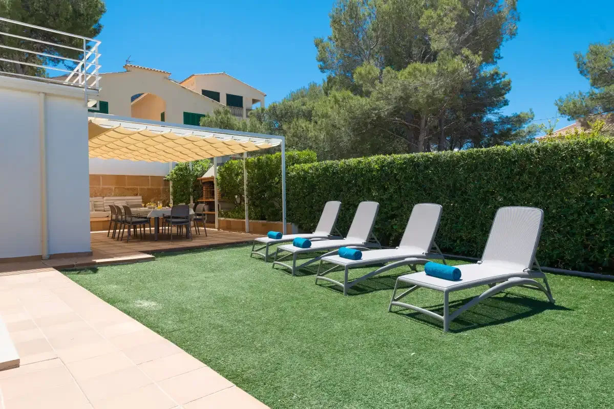 A sunny outdoor patio with lounge seating on the lawn beside a shaded dining area.