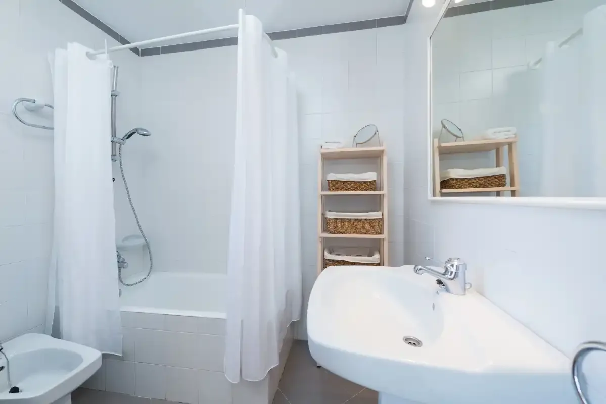 A bright bathroom with a bathtub, shower, and wall-mounted sink.