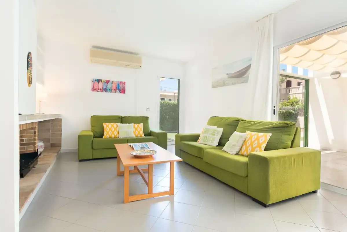 A bright living room with green seating and a wooden coffee table.