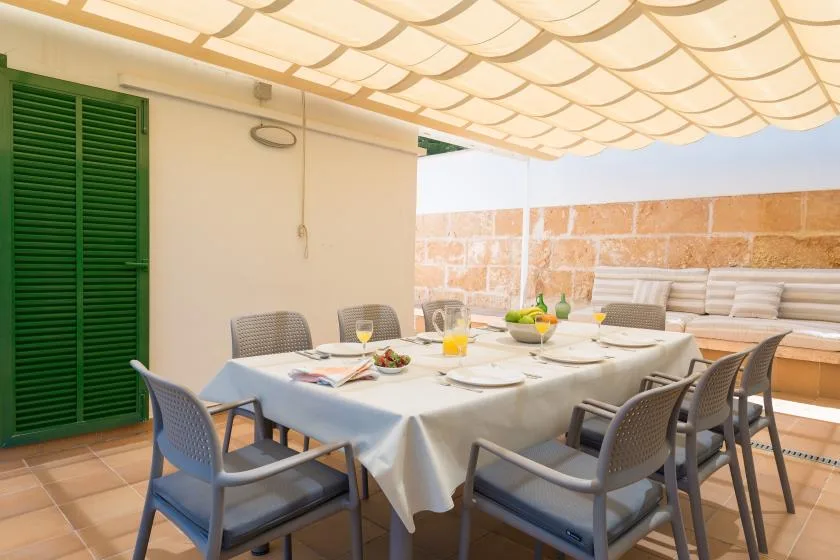 A covered outdoor dining area with a large table and surrounding seating.