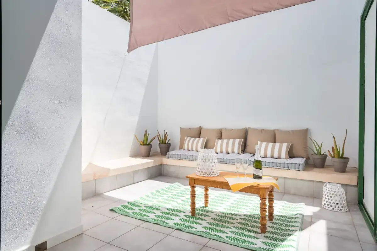 A bright patio seating area with a low table and patterned rug.