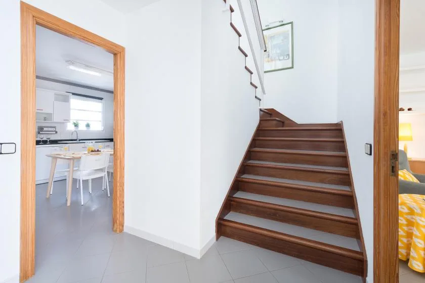 A bright interior hallway connects a wooden staircase with an open dining area.