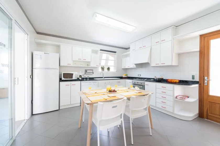A bright kitchen with white cabinets, a counter, and a dining table.