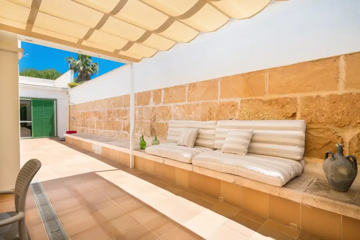 A covered outdoor patio with built-in seating and a stone-tiled wall.