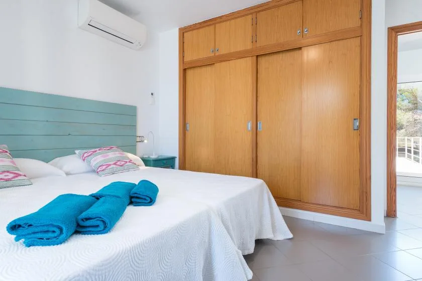 A bedroom with two beds, turquoise towels, and a built-in wooden wardrobe.