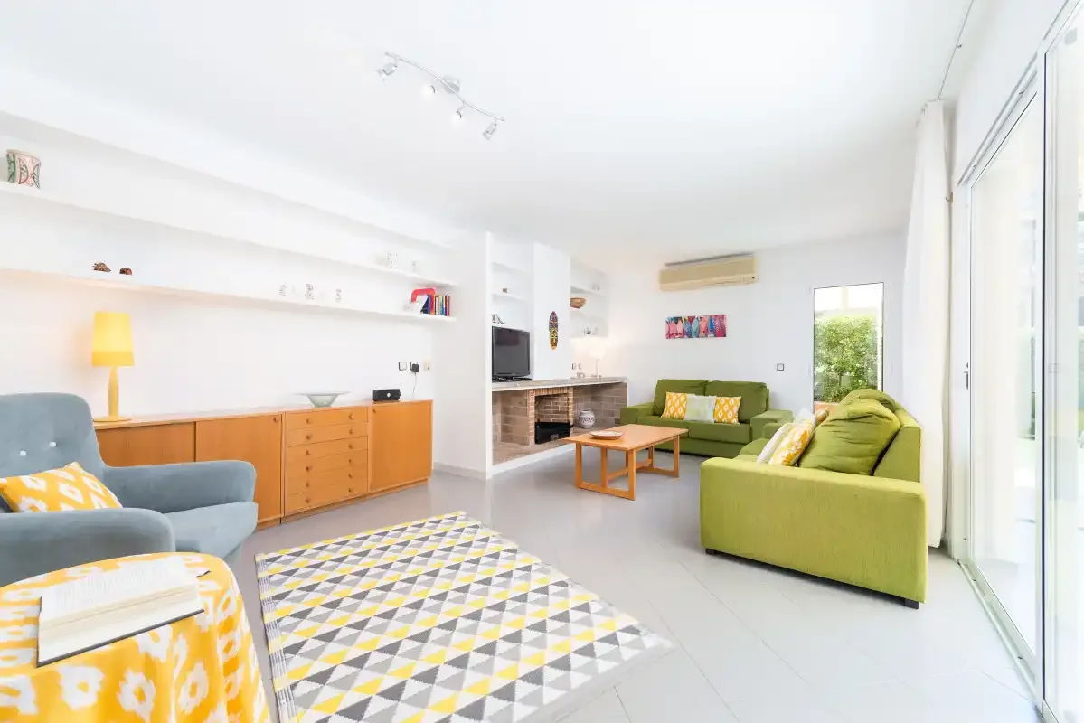 A bright living room with colorful seating, a coffee table, and large windows.