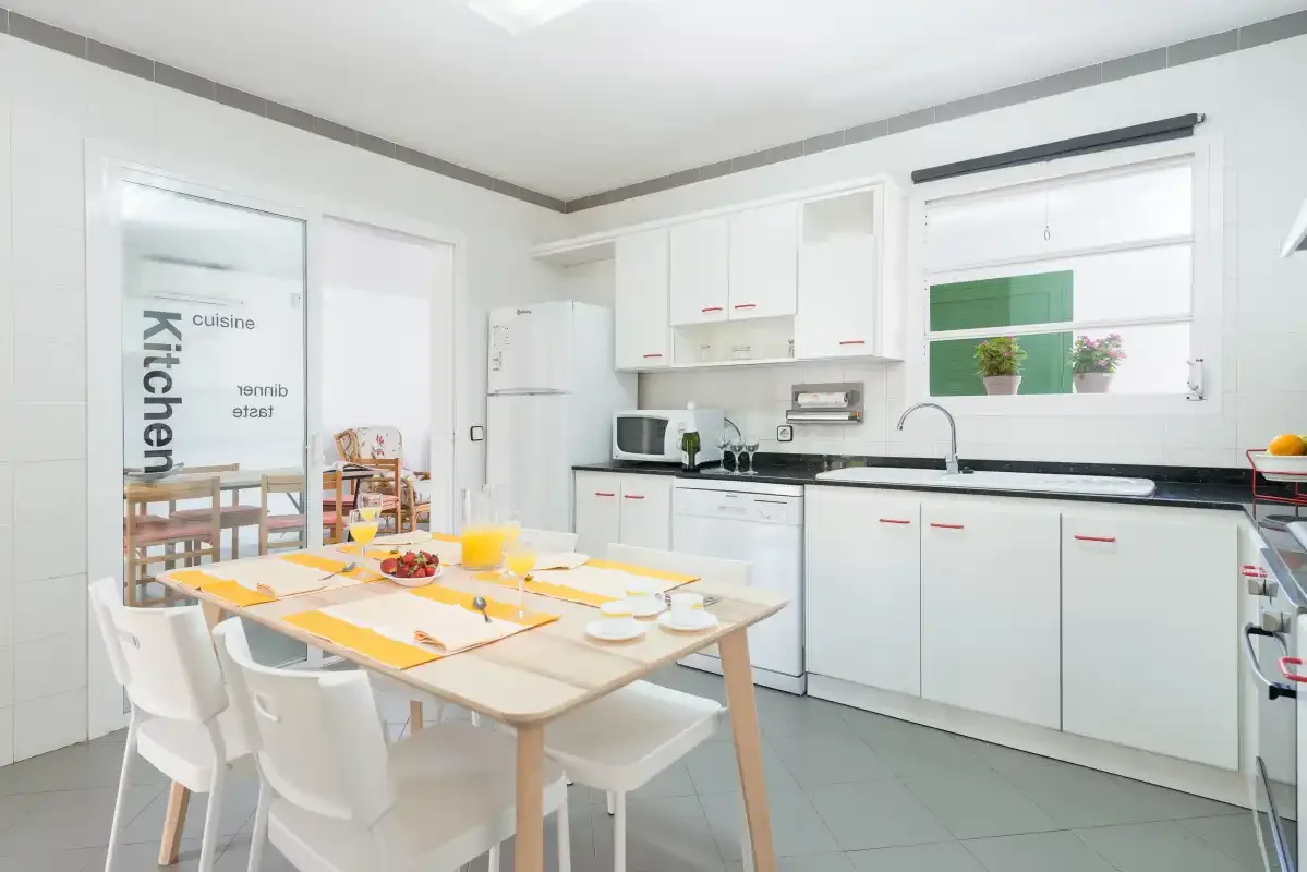 A bright kitchen and dining area with white cabinets and a table set for a meal.