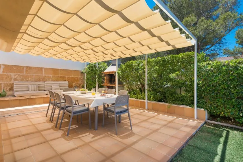 A tiled outdoor patio has a dining table beneath a fabric shade canopy.