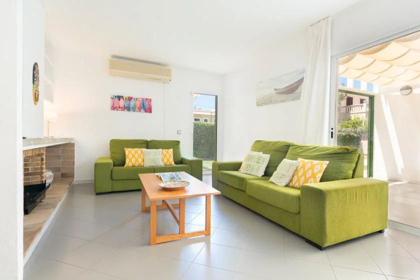 A bright living room with green seating and a wooden coffee table.