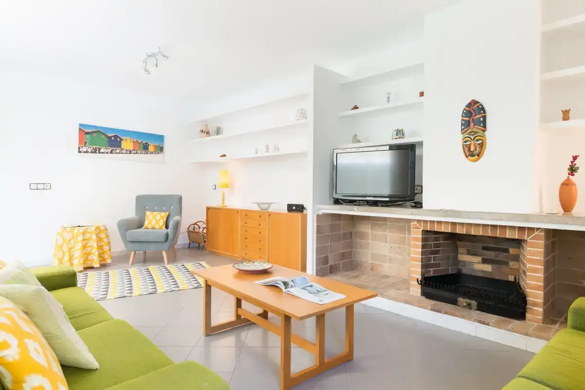 A bright living room with a television, fireplace, and seating.