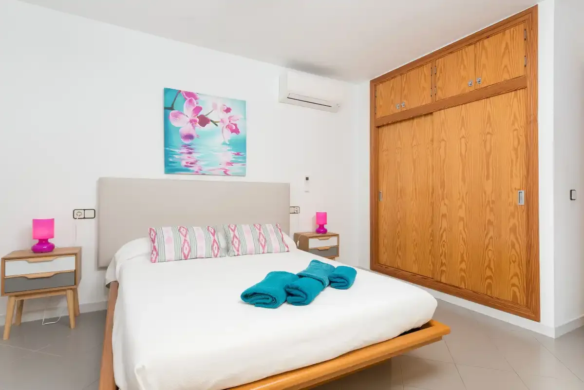 A bedroom with a bed, bedside tables, and a large wooden wardrobe.