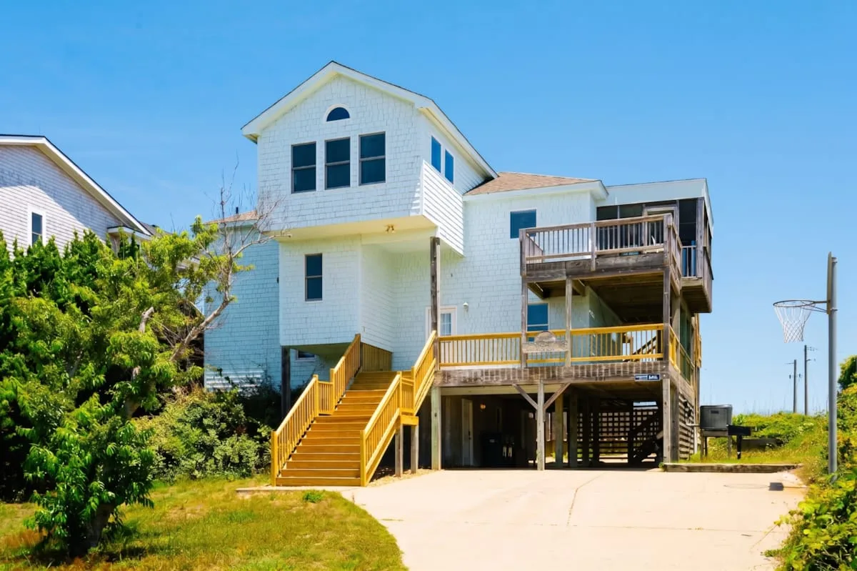 Una casa elevada de estilo costero con escaleras exteriores y una terraza de madera.