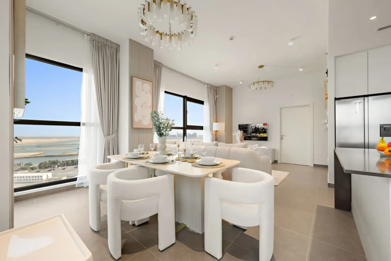 Un comedor luminoso con la mesa puesta junto a grandes ventanales con vistas al agua.