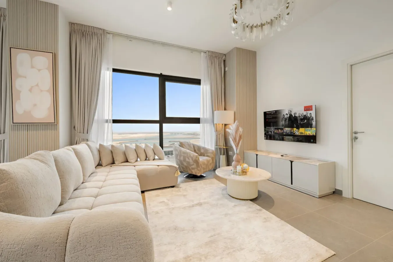 A bright living room with seating arranged around a low coffee table and a large window.