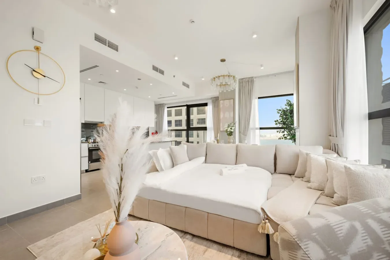 Una sala luminosa con un amplio sofá seccional blanco y ventanas altas.