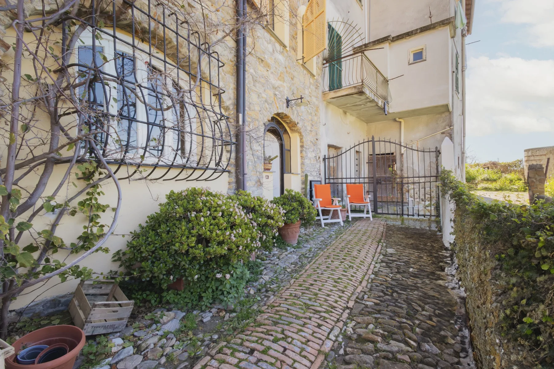 A cobblestone courtyard beside a stone building, with outdoor seating and greenery.