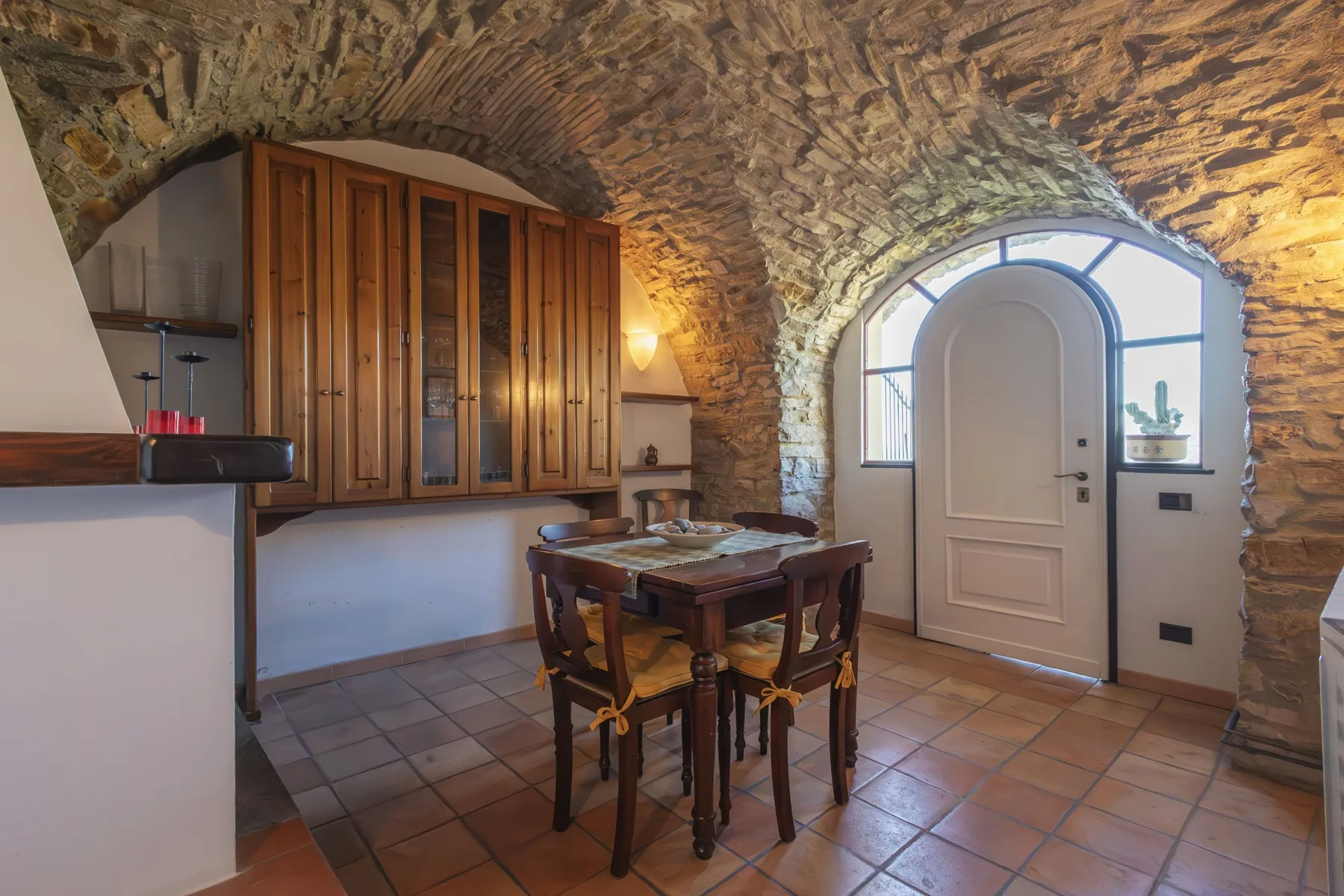 A dining area with a wooden table beneath a stone vaulted ceiling.