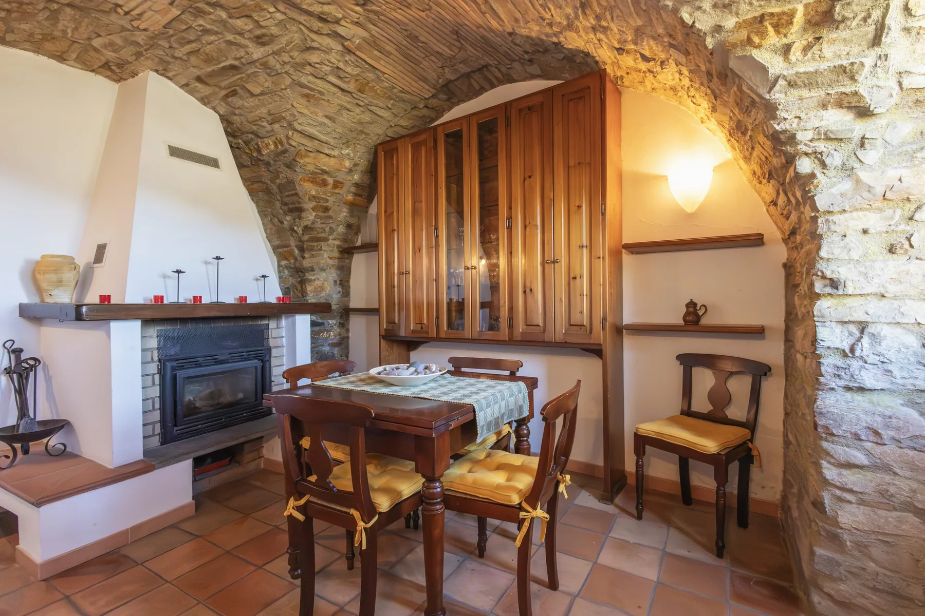 A rustic dining area with a wooden table beneath a stone arch.