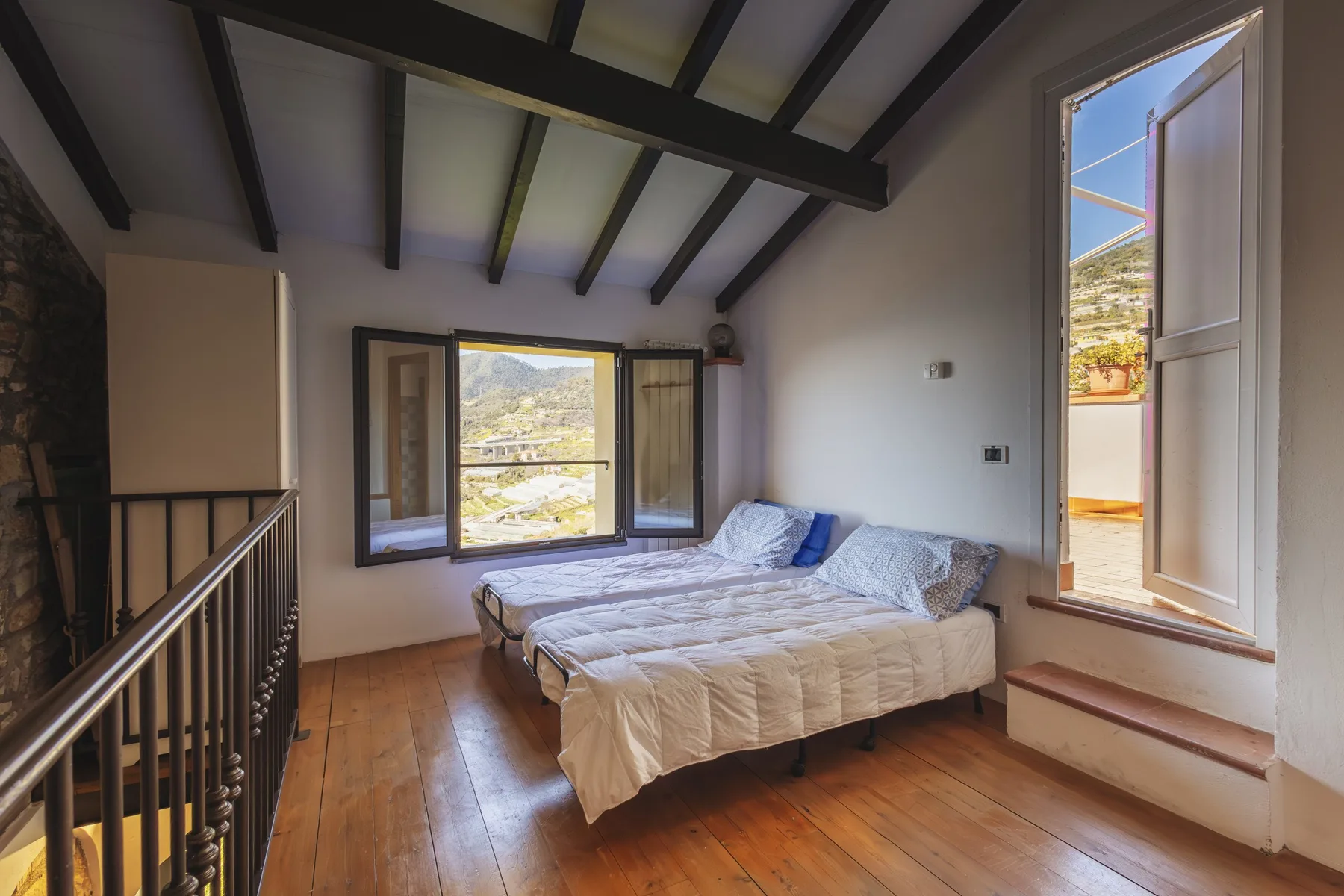 A bedroom with a bed beside a large window and an open casement.