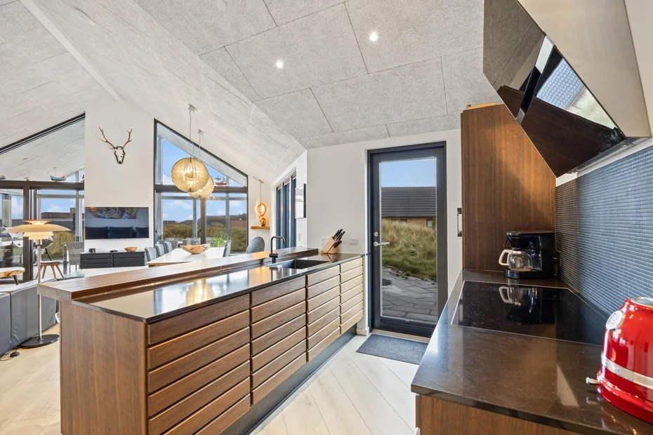 Una cocina moderna con una isla larga y grandes ventanales.