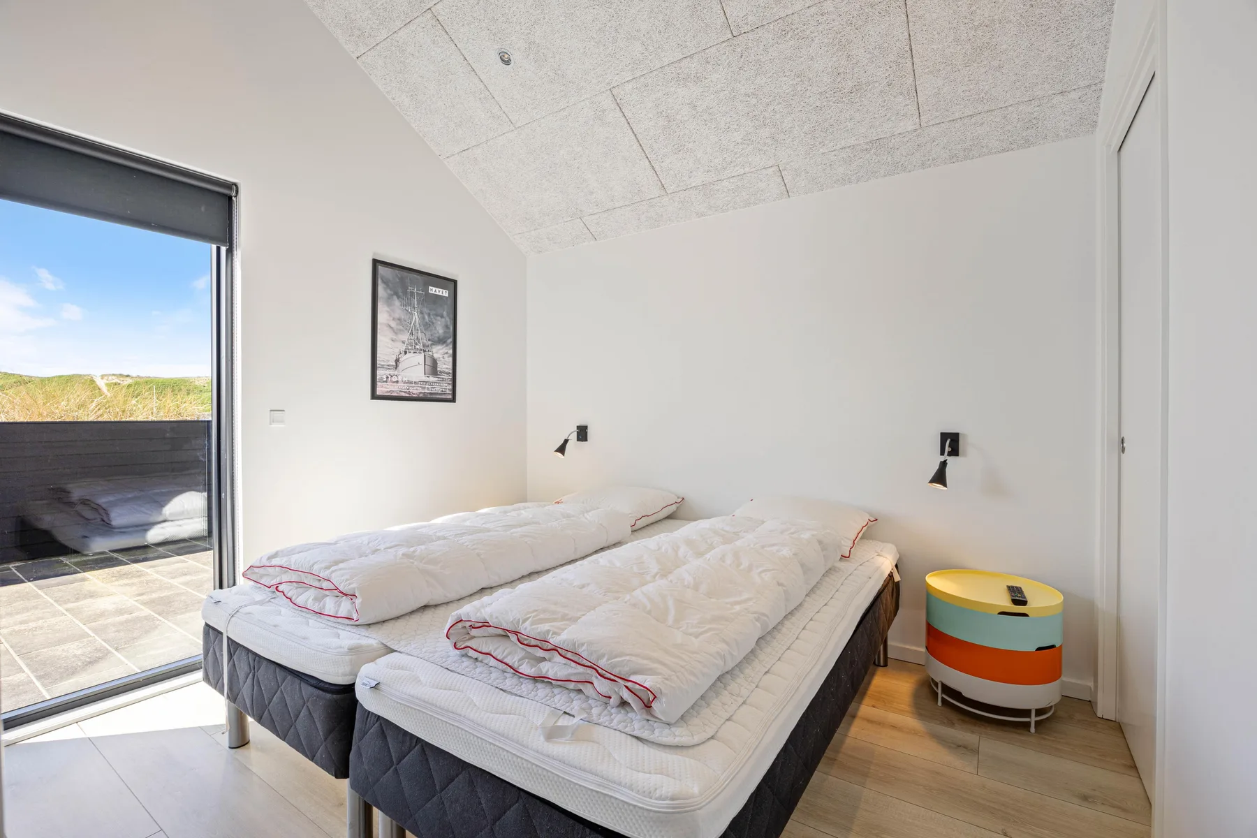 Un dormitorio luminoso con dos camas junto a una gran puerta de vidrio.
