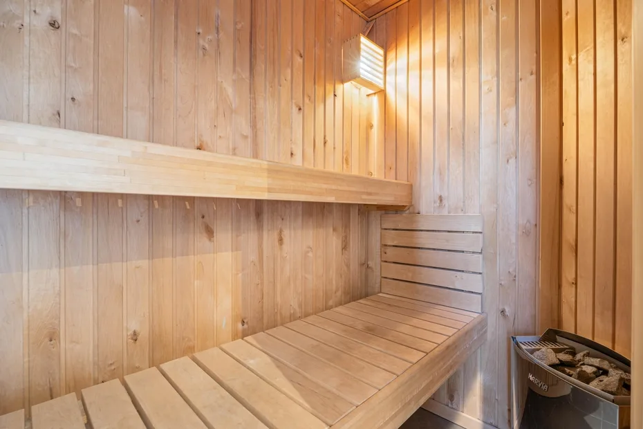 Una sauna revestida de madera con bancos escalonados y una luz en la pared.