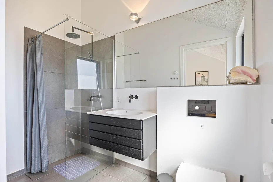 Un baño moderno con ducha de vidrio y lavabo flotante.