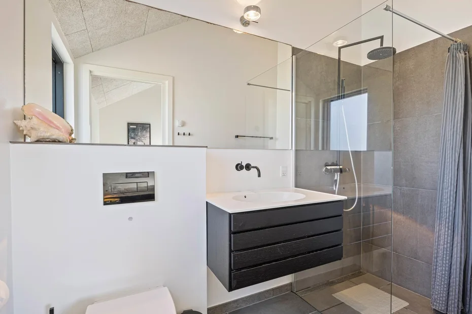 Un baño moderno con un lavabo suspendido y una ducha de cristal.