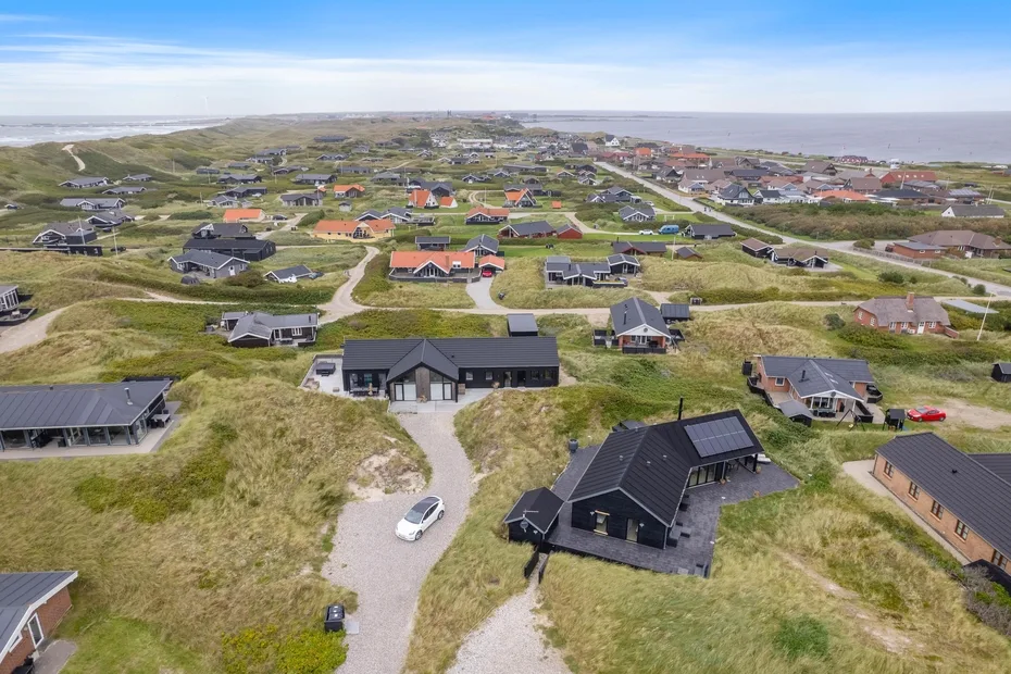 Vista aérea de casas dispersas por un paisaje costero cubierto de hierba.