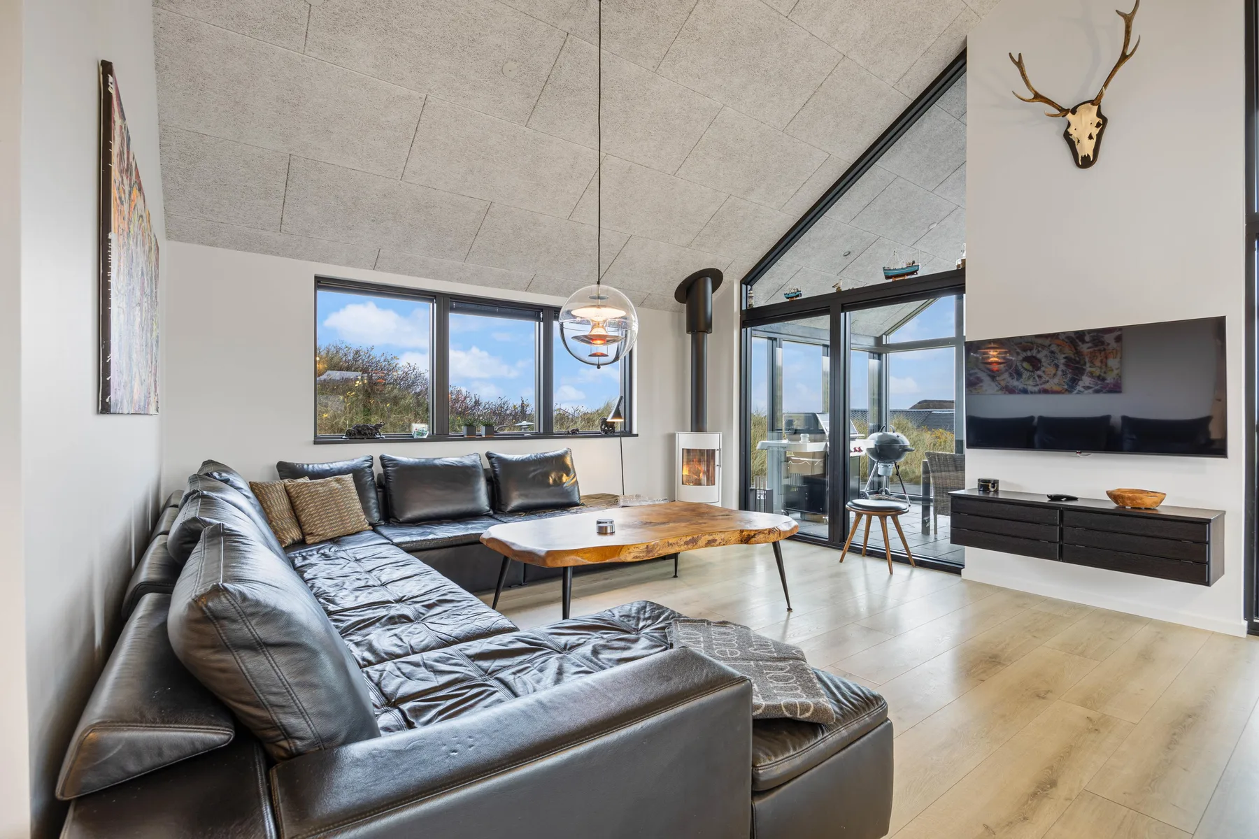 Una sala luminosa con un sofá seccional grande y ventanas con vistas al exterior.