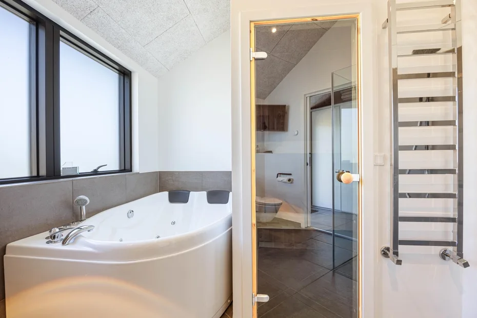 Un baño con una bañera esquinera y una ducha con panel de vidrio.