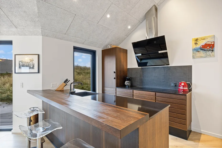 Una cocina moderna con una isla de madera, gabinetes oscuros y una placa de cocina.