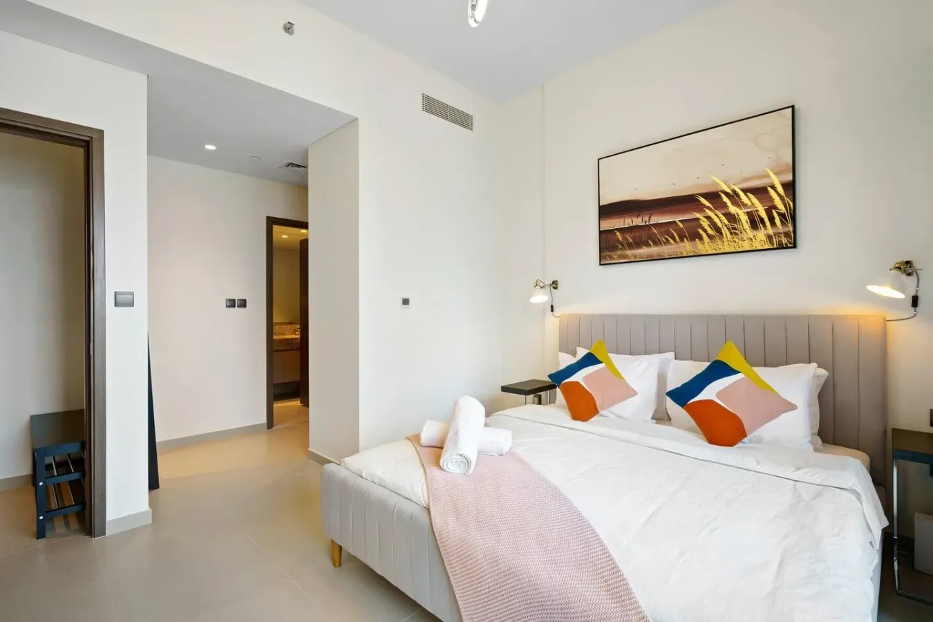 Un dormitorio con una cama bien arreglada y un cuadro sobre el cabecero.