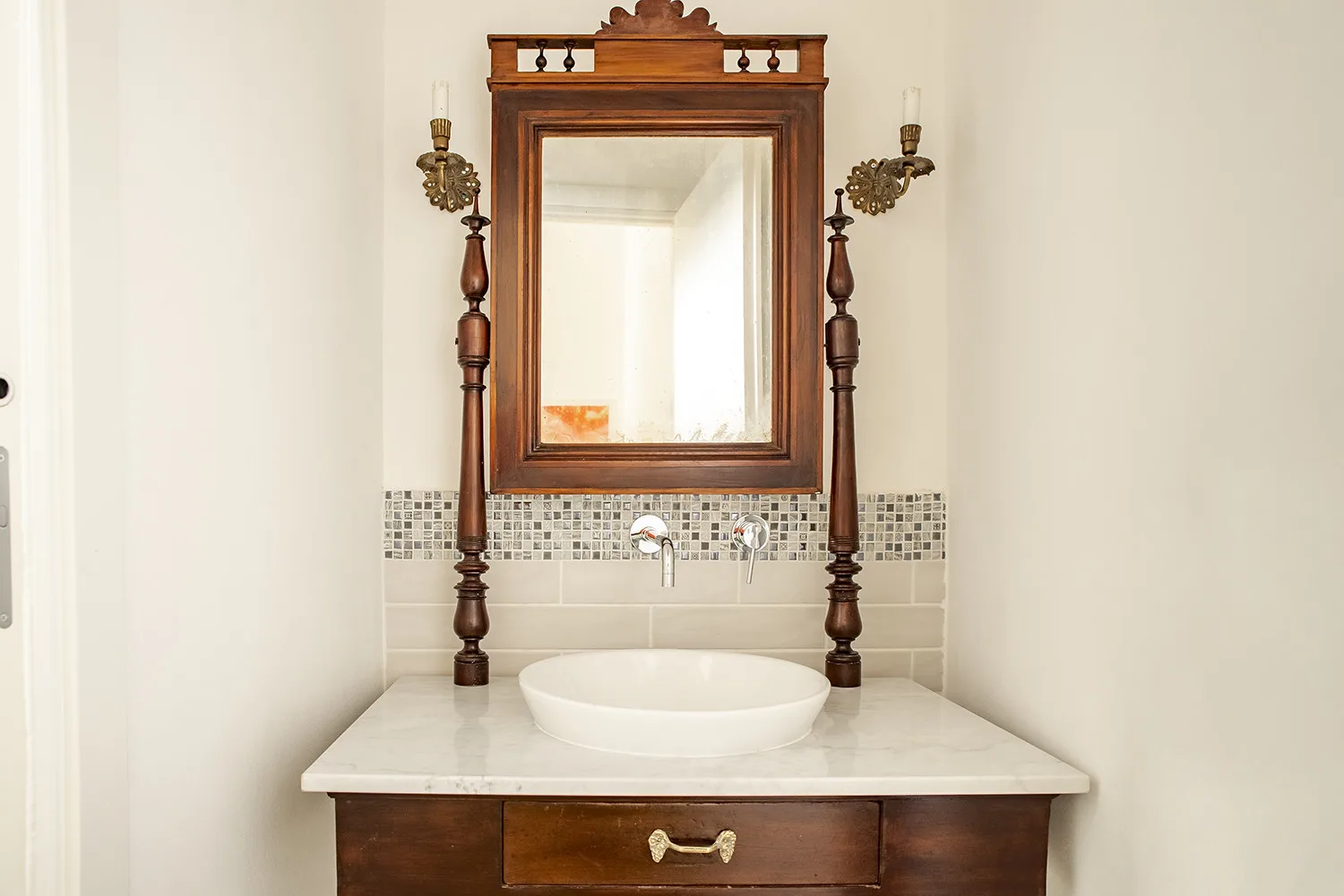 Un mueble de baño con lavabo blanco está debajo de un espejo grande enmarcado.
