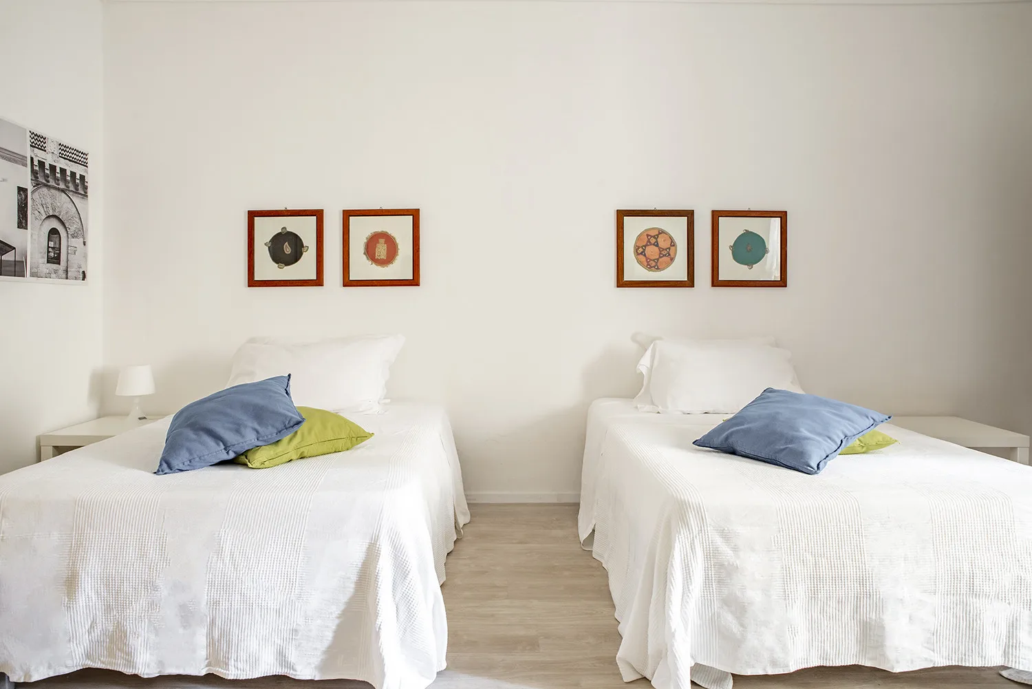 Un dormitorio luminoso con dos camas y cuadros en la pared.