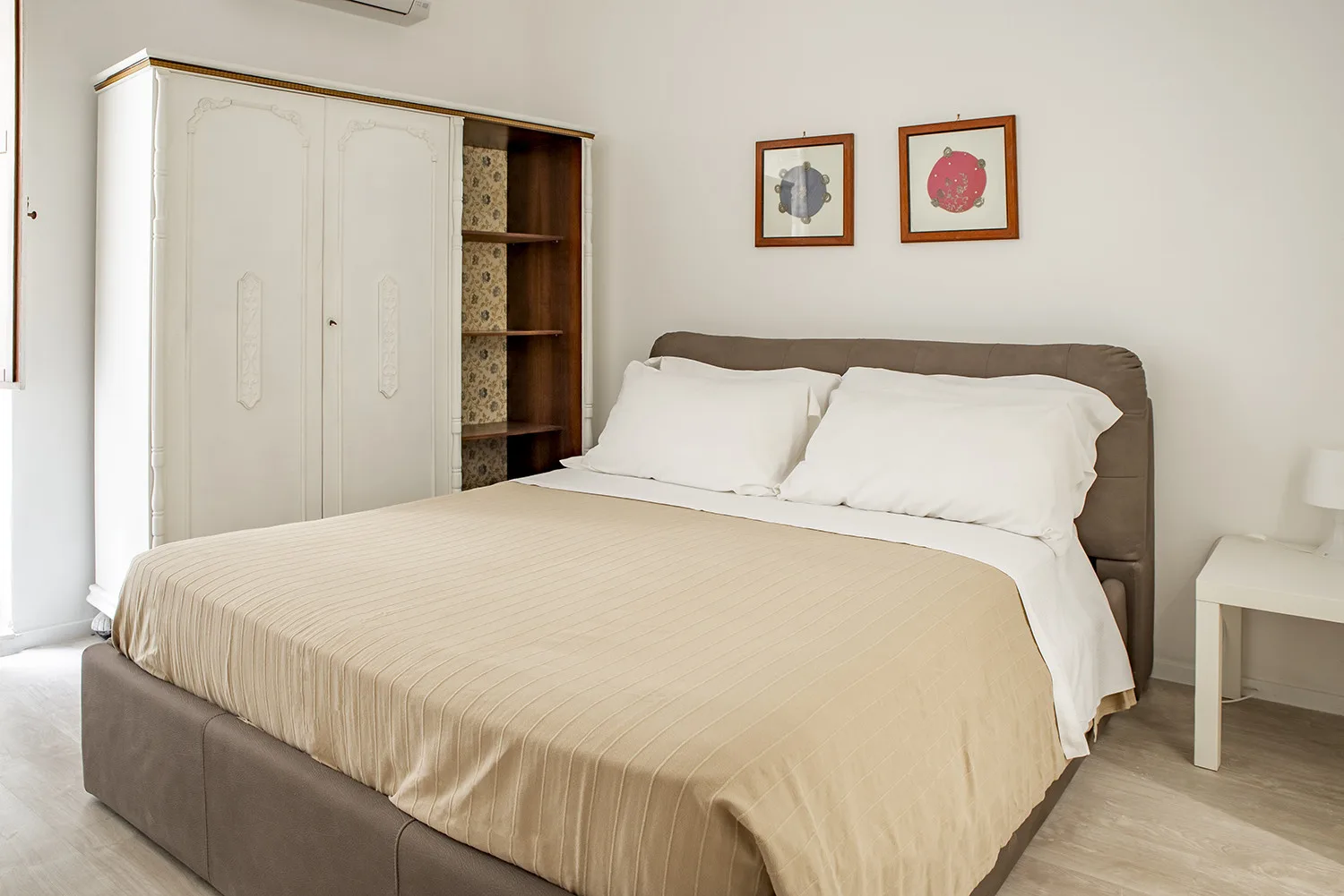 Un dormitorio con una cama grande, almohadas blancas y un armario.