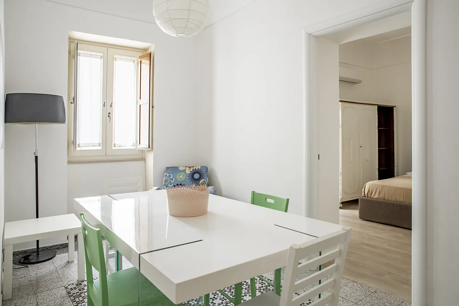 Un comedor luminoso con una mesa blanca y una ventana.
