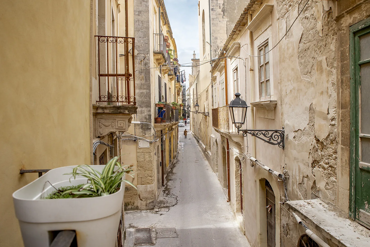 Una calle estrecha de piedra pasa entre edificios muy próximos, con un farol colgante.