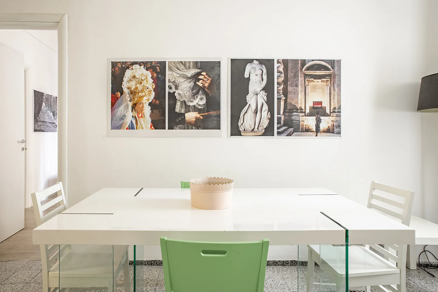 Un comedor luminoso con una mesa blanca, asientos verdes y obras enmarcadas.