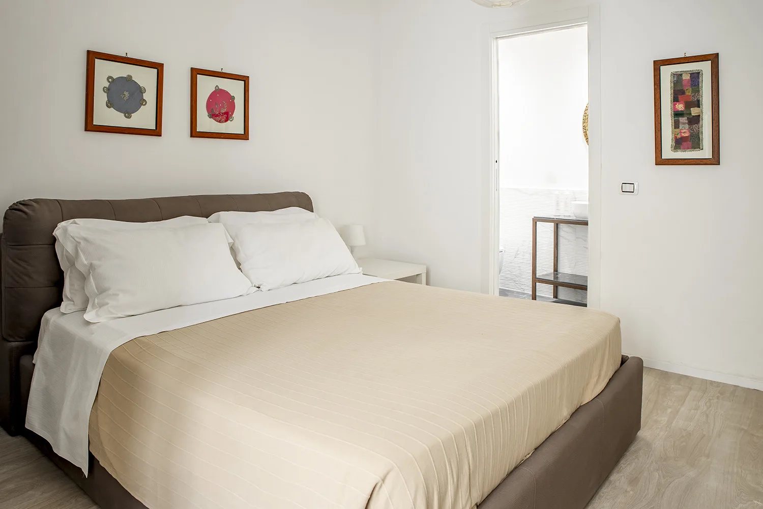 Un dormitorio con una cama bien hecha y cuadros en las paredes.