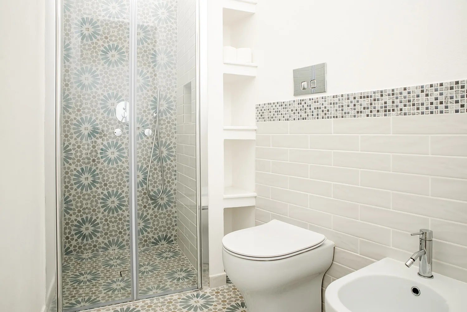 Un baño luminoso con una ducha estampada y paredes de azulejos blancos.